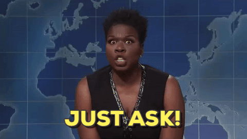 Leslie Jones on SNL Weekend Update talking to camera with words "JUST ASK!" at bottom of image
